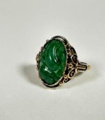 An 18ct gold dress ring set oval relief carved jadeite carved panel (2cm x 1cm) mounted in open work