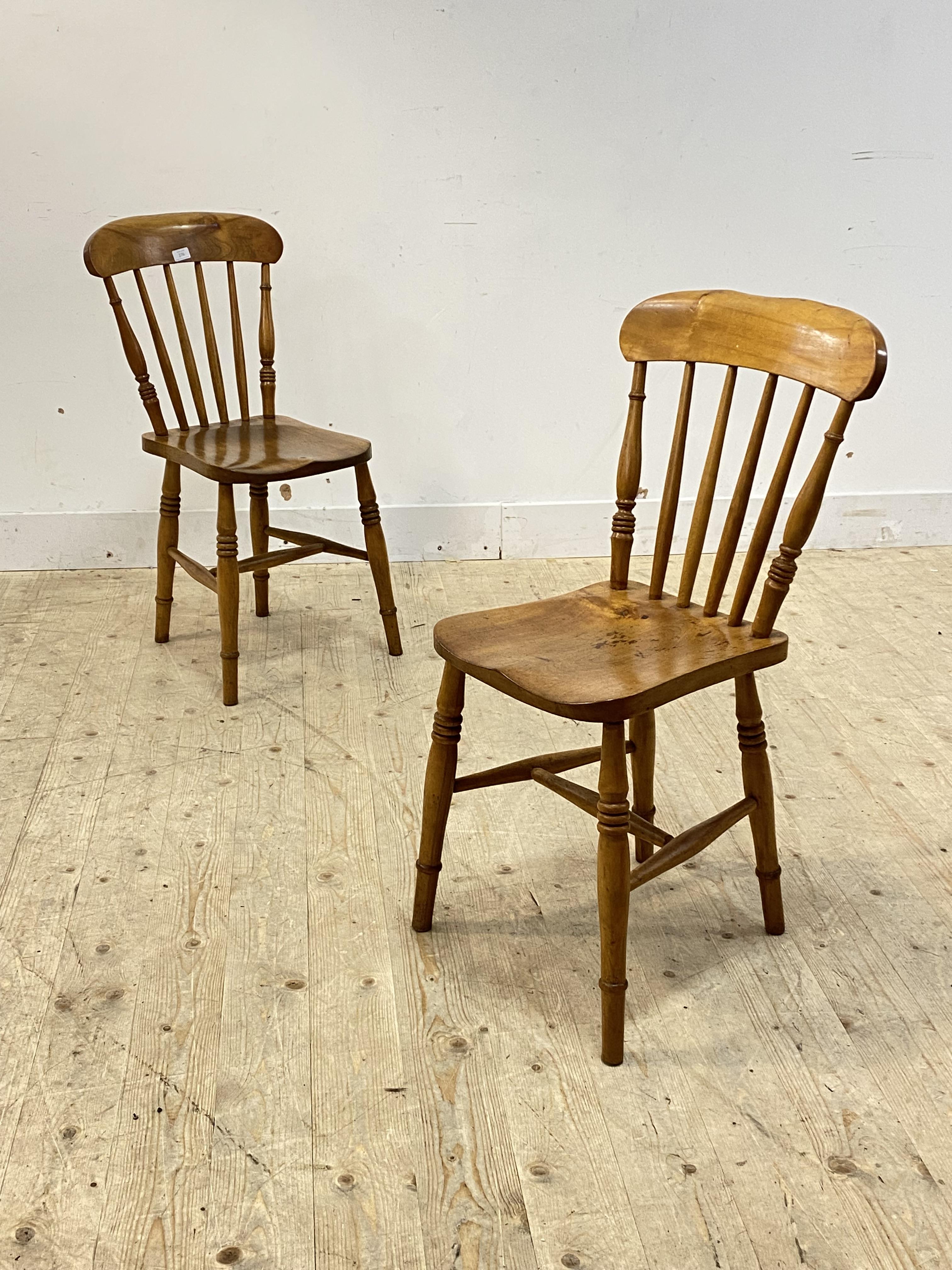 A pair of late 19th century farmhouse chairs, probably sycamore, with spindle back over saddle seat,