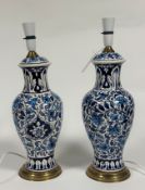 A pair of ceramic lamps in baluster form decorated with persian style floral displays raised on a