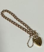 A 9ct gold curb link bracelet complete with 9ct gold engraved heart shaped padlock and safety chain,