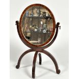 A 19thc mahogany oval dressing mirror on folding bipod support, with scroll suppots, (41cm x 28cm)
