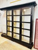 A large contemporary ebonised ash glazed cabinet, the dentil cornice over three doors, each