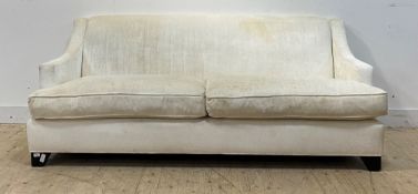 A contemporary high back sofa, upholstered in ivory velure, raised on ebonised bracket supports,