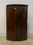 A Georgian mahogany bow front wall hanging corner cabinet, the dentil cornice over inlaid frieze and