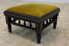 An Aesthetic period ebonised footstool with upholstered top, spindle apron and turned supports, with