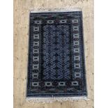 A Turkoman hand knotted wool rug, the blue field of repeating lozenges with stylised floral motif to