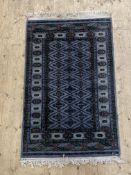 A Turkoman hand knotted wool rug, the blue field of repeating lozenges with stylised floral motif to