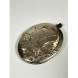 An Edwardian white metal engraved oval locket with fern and flower design, (L: 6cm x 4.5cm)