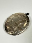 An Edwardian white metal engraved oval locket with fern and flower design, (L: 6cm x 4.5cm)