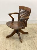 An early 20th century oak desk chair, the shaped crest rail over spindle back, sweeping open arms