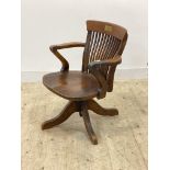 An early 20th century oak desk chair, the shaped crest rail over spindle back, sweeping open arms