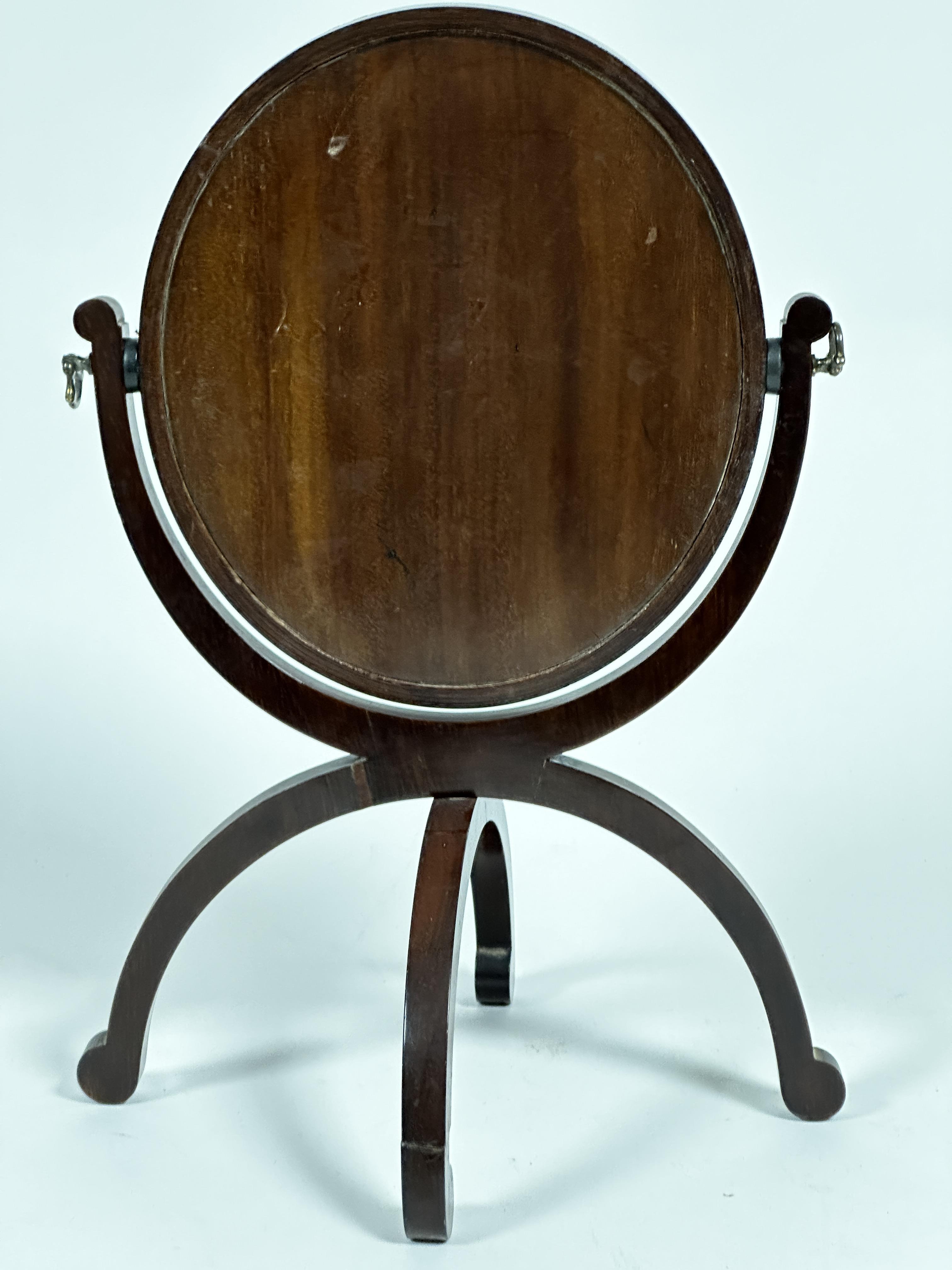 A 19thc mahogany oval dressing mirror on folding bipod support, with scroll suppots, (41cm x 28cm) - Image 2 of 3