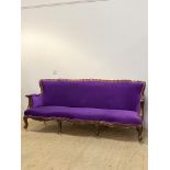 A Baroque style sofa, with undulating crest rail and scrolled arms enclosing purple velvet