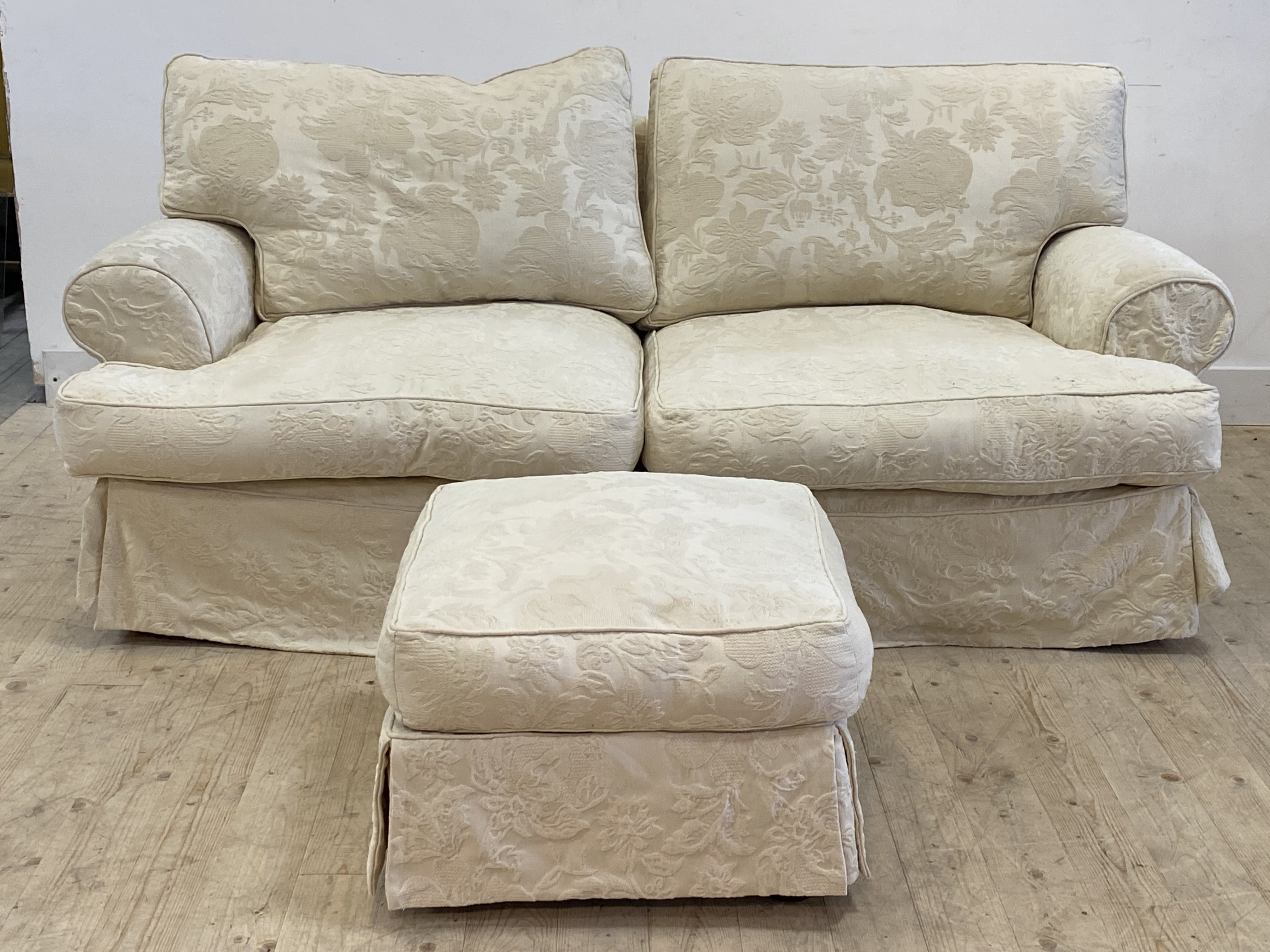 A traditional two seat sofa, upholstered in a fitted white damask cover, raised on turned bun