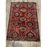 A Persian hand knotted rug, with triple pole medallion on a red field decorated with stylised