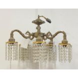 An early 20th century cast brass chandelier, with five 'S' scrolled branches, each having lustre