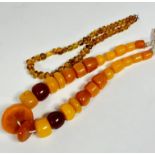 A clear amber glass bead necklace, (L: 20cm) a yolk and dark amber coloured Eastern necklace with