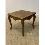 A walnut side table of serpentine outline in the French taste, floral carved and raised on