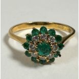 An 18ct gold emerald and diamond cluster ring, centre emerald (approx 0.2ct) mounted in claw setting