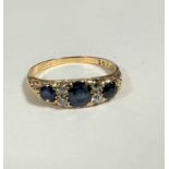 A yellow metal sapphire and diamonnd ring, with three graduated sapphires and four stone and two old