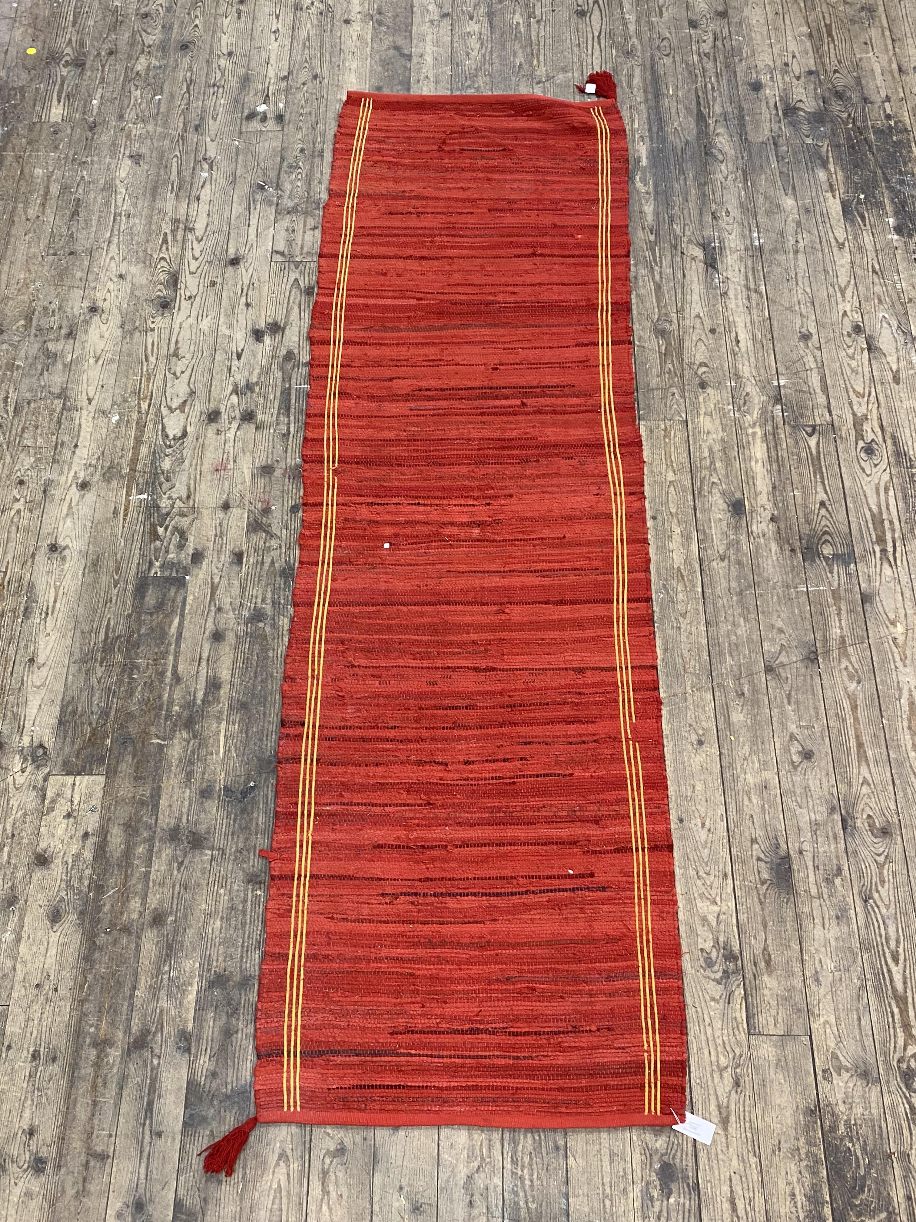 A red ground flat weave runner rug