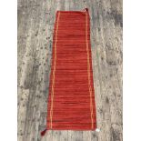 A red ground flat weave runner rug