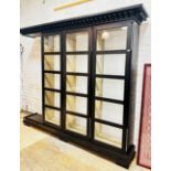 A large contemporary ebonised ash glazed cabinet, the dentil cornice over three doors, each
