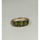 A 9ct gold peridot three stone ring with diamond set spacers, the centre stone approximately 0.