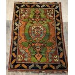 A Kazak hand knotted rug, the green and orange field enclosed by a deep blue border with repeating