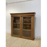 An early 20th century oak bookcase, the projecting cornice over two glazed doors enclosing two