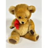 An unmarked golden mohair plush teddy bear with inset glass eyes, stitched nose and mouth, and