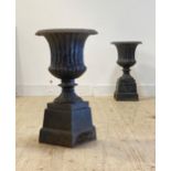 A pair of black painted cast iron campana urns, with egg and dart moulded flared rim, fluted body