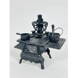 A reproduction miniature cast iron 19thc stove complete with sauce pan, soup pan with loop handle,