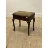 An early 20th century walnut music stool, the hinged top opening to a well, raised on cabriole