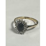 A 9ct gold sapphire and diamond cluster ring, the oval sapphire approx 0.4/0.5 ct, with surround