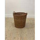 A large wicker twin handled log or laundry basket of tapered cylindrical outline, H57cm