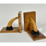 A pair of treen bookends with book fluted spines and curved ebonised horn style supports with