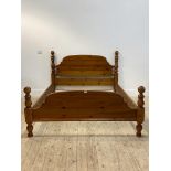 A polished pine 5' double bed, the panelled head and foot board with turned ball finials, H109cm,
