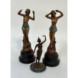 A set of two Art Deco cast bronze figures both of a lady standing with her arms up raised on a