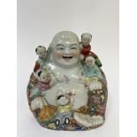 A Chinese porcelain laughing Buddha modeled with five Tang children and decorated with flowers in