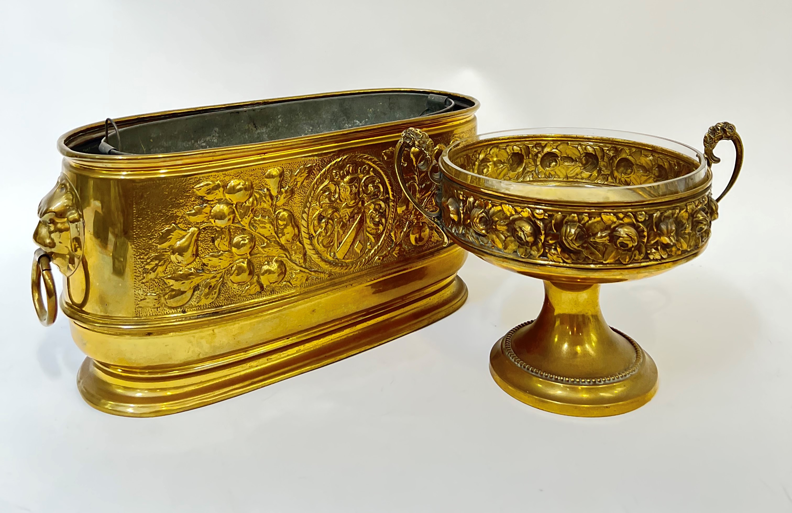 A brass trough/planter and liner with heraldic design in relief and lion's head/loop handles (h-