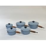 A group of five Le Creuset cast iron pans with duck egg blue enamelling with wooden handles,