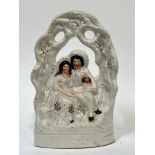 A Staffordshire flatback model of a marriage depicting a man and woman with Spaniel dog under a