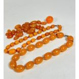 An amber coloured bead necklace, (L: 19cm, each bead approximate L: 2.5cm, d: 1.5cm) a graduated