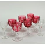 A set of six Edwardian cranberry glass to clear cut glass wine glasses on faceted stems and