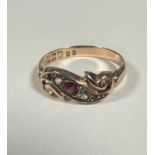 A 9ct gold S shaped scroll ring with pink set stone, flanked by two paste set stones and two pink
