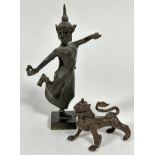A Balinese cast bronze dancing figure with traditional flaming headdress, holding a pear with foot