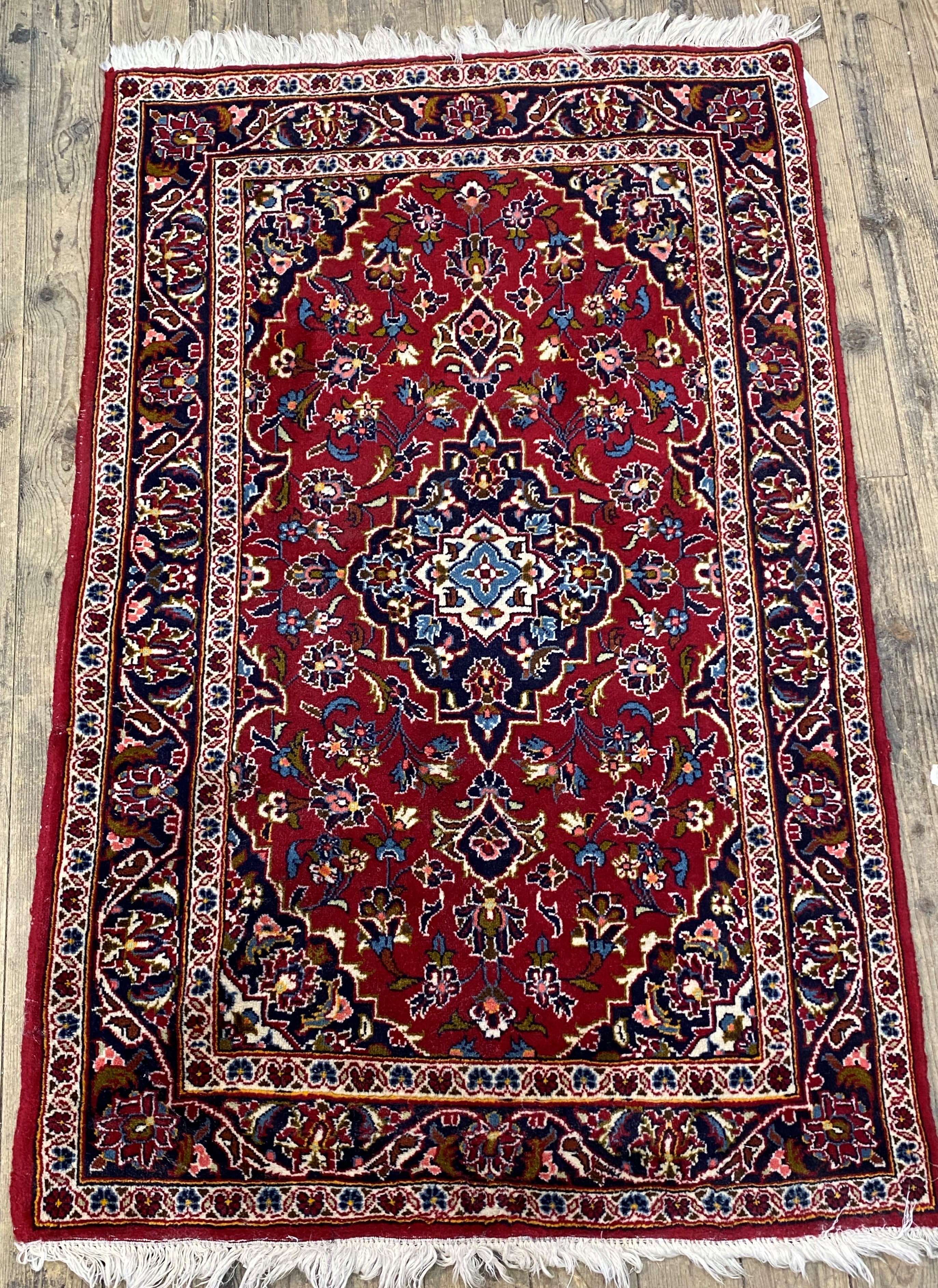 A Persian Kashan design rug, the red field with blue medallion and spandrels, within a guarded