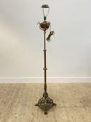 An late Victorian brass and copper lamp standard, on hairy paw cast supports, converted from oil,