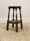 An early 20th century oak stool, the lozenge and floral carced circular seat riased on turned and